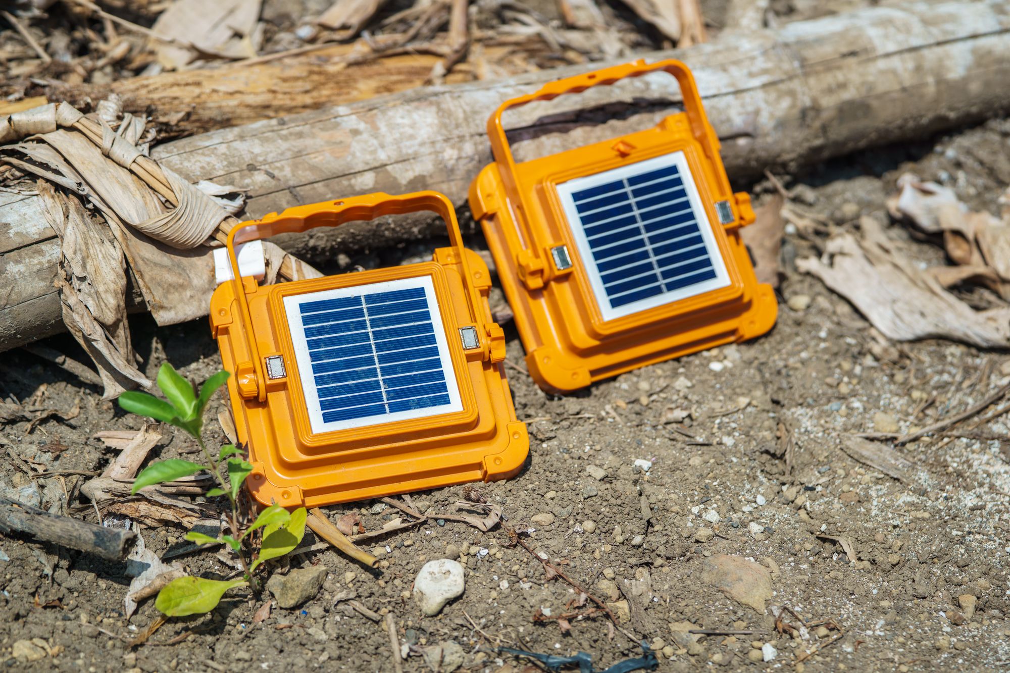 Two orange portable solar panels set up on dry ground