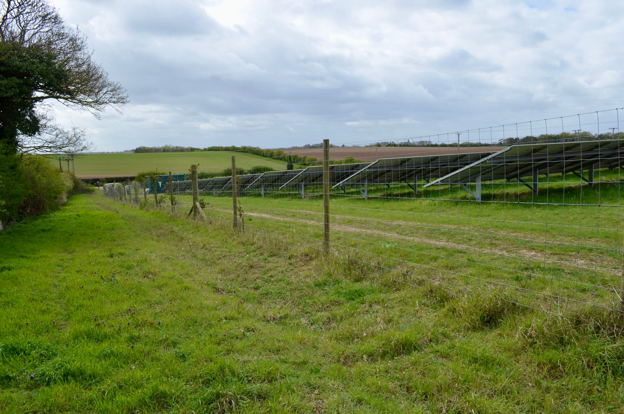Solar panels installed in a rural field under a cloudy sky