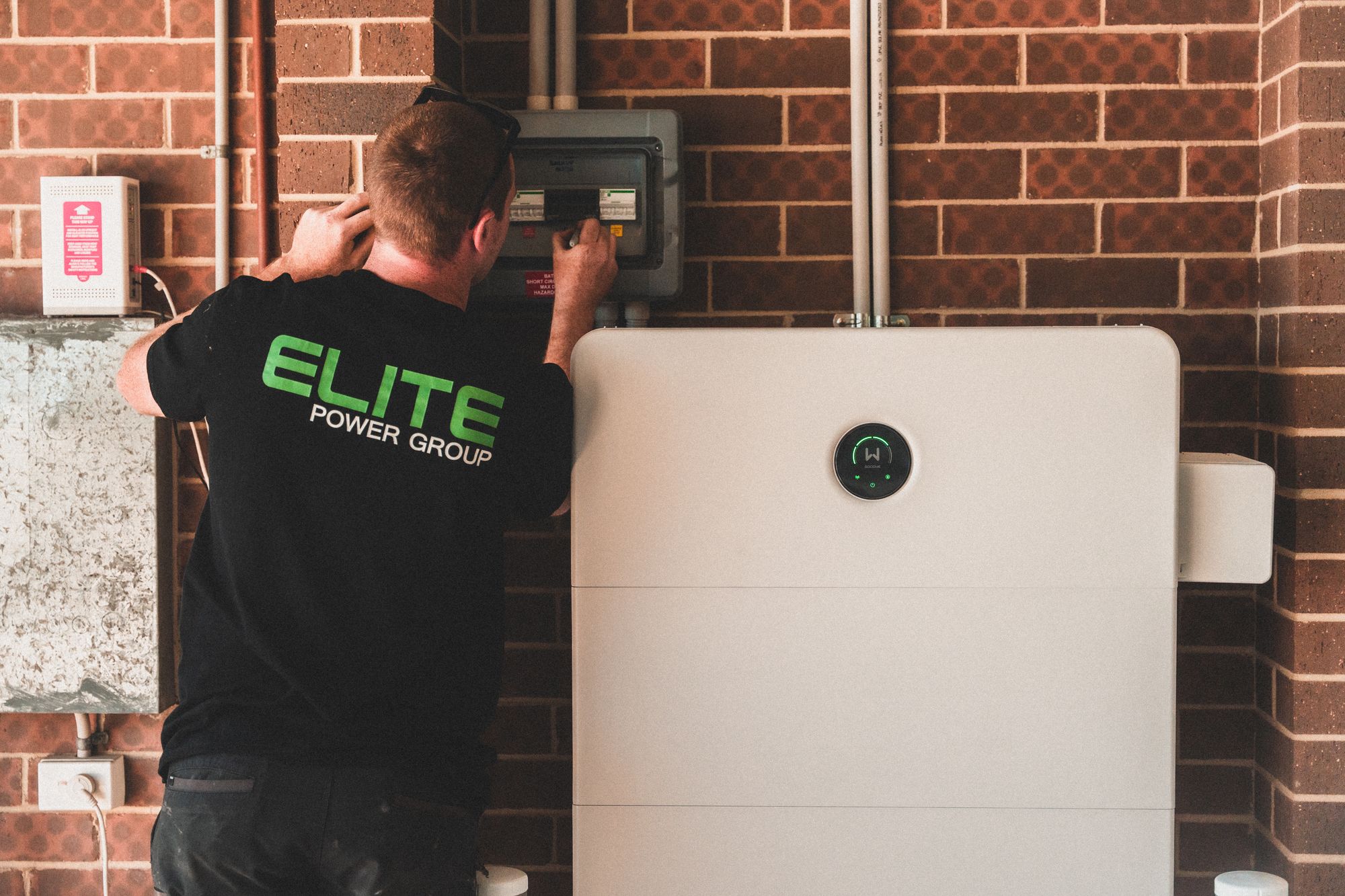 An electrician installing a home energy battery storage unit