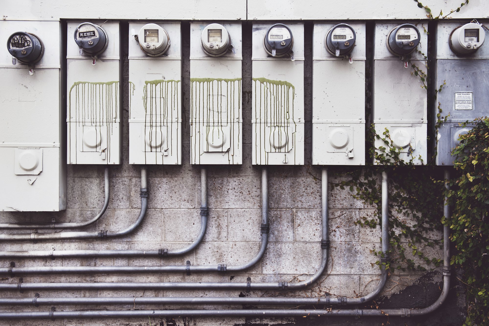 A row of gray electricity meters mounted on a wall