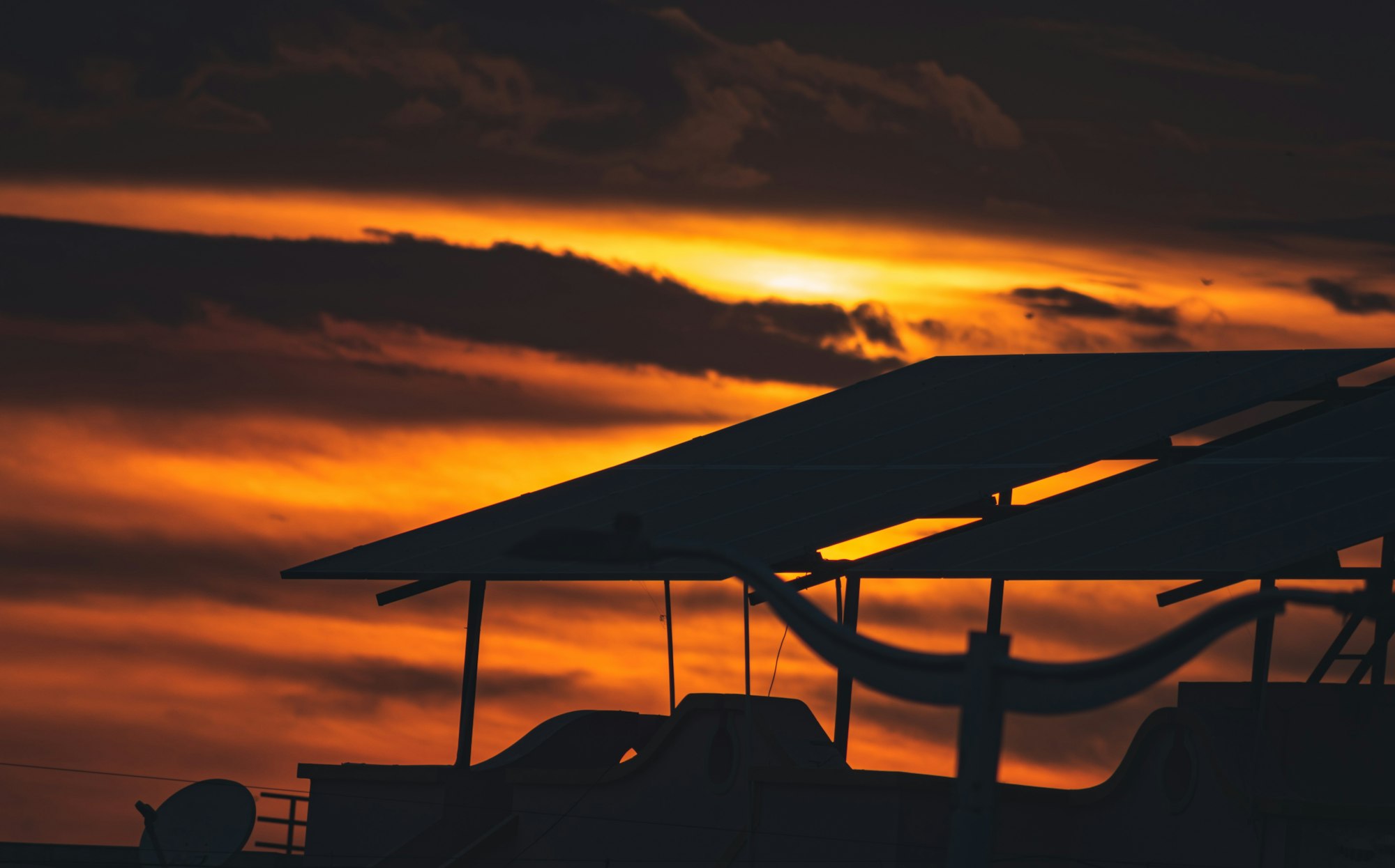 The sun setting behind a rooftop solar panel